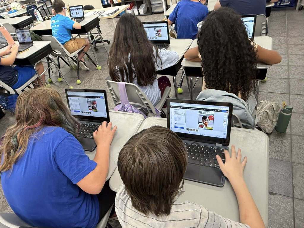 students sitting at their desks working on their computers creating with Canva