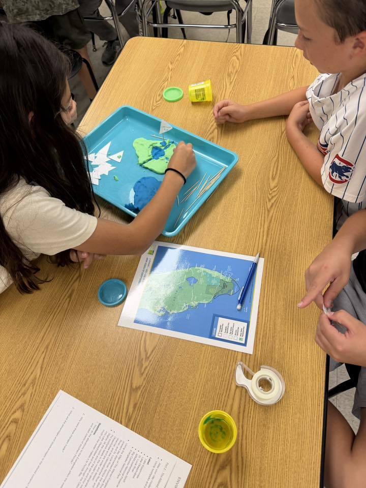 Students sitting at a table forming clay