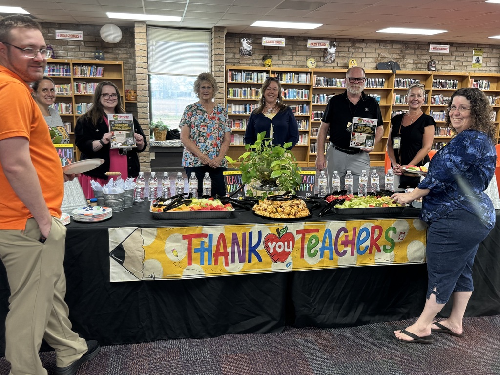teachers standing in front of food table with a sign that says thank you teachers on