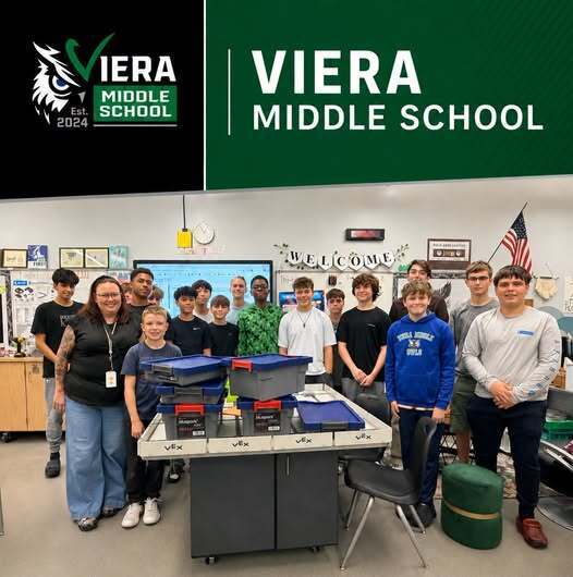 Middle school boys and female teacher surrounding a table that has Sphero Blueprint kits on it
