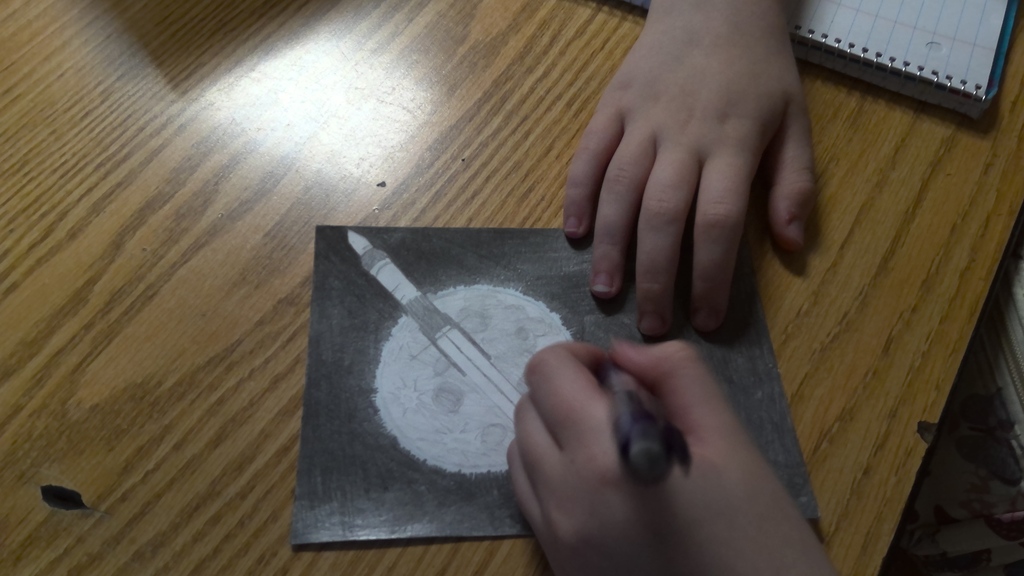 image a student working on drawing an image that will go into space.