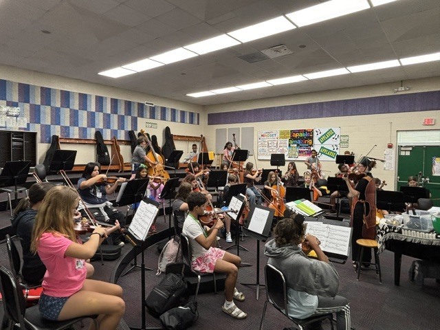 students holding orchestral instruments