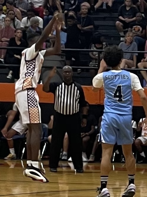 image of two basketball players and a referee in action on basketball court