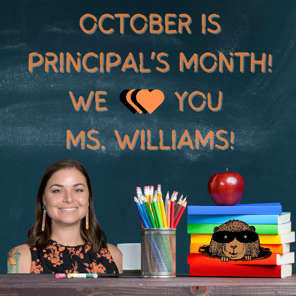 image of ms. williams in front of a chalkboard with books pensils apple gopher logo and the words we heart you ms. williams.