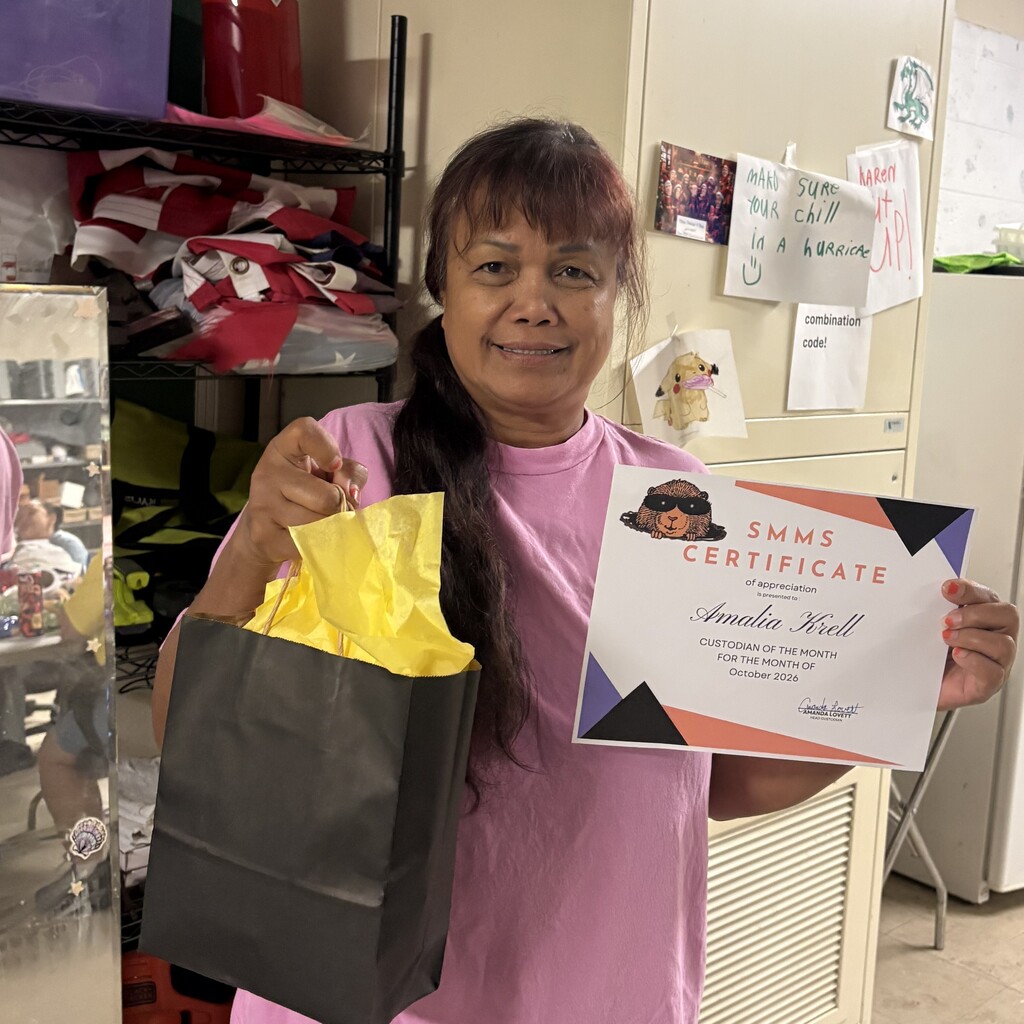 Image of Ms. Krell holding a certificate and gift bag