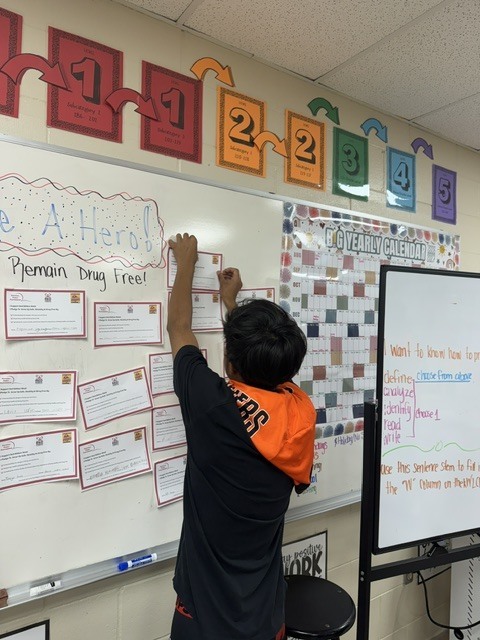 image of a stone student standing at a whiteboard pinning up his drug free pledge card