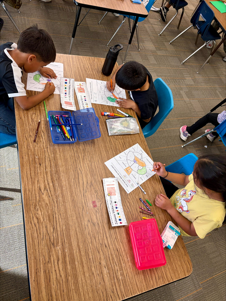 Three elementary students complete human brain coloring worksheets during a science activity.