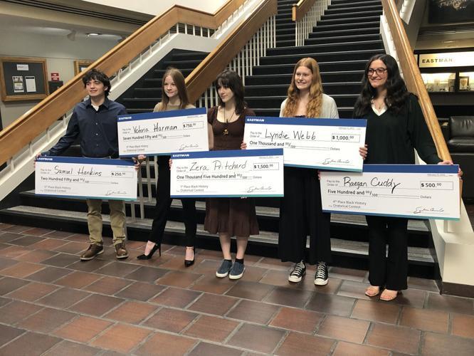 This is a photo of the winners of the Eastman Oratorical Contest. They are holding large checks that represent their winnings.