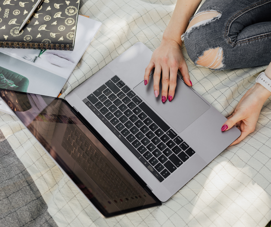 The photo shows an open laptop sitting on top of a blanket. A female appears to be using the laptop.
