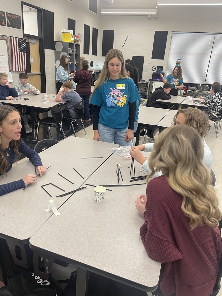 Students collaborate at classroom tables while engineers from Eastman Chemical Company circulate to help during a hands-on bridge-building challenge for Engineers Week.