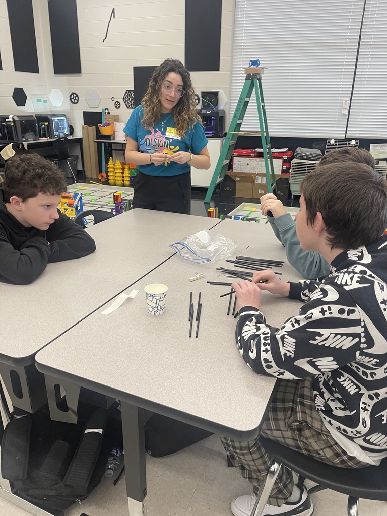 An engineer from Eastman Chemical Company speaks with two Tennessee Middle School students as they plan their bridge design using small rods and tape during an Engineers Week STEM activity.