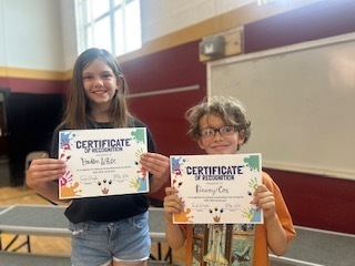 Two students stand together holding Certificates of Recognition.