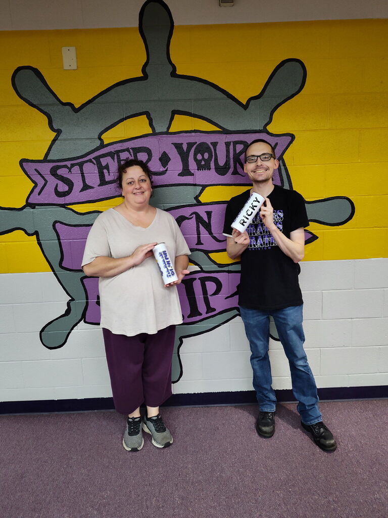 Two members of the custodial staff hold cups given as a gift for their special day.