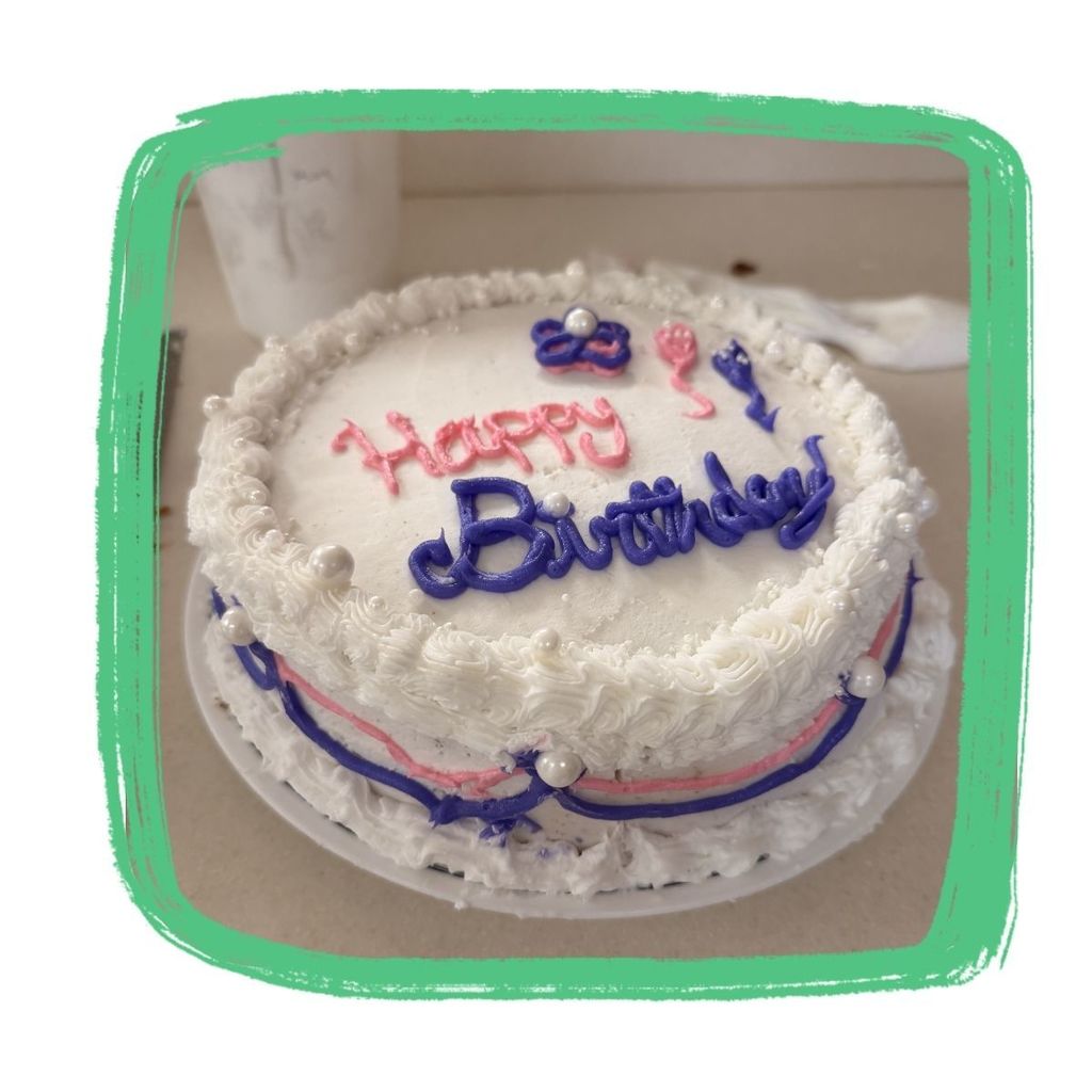 White cake with cursive lettering happy birthday