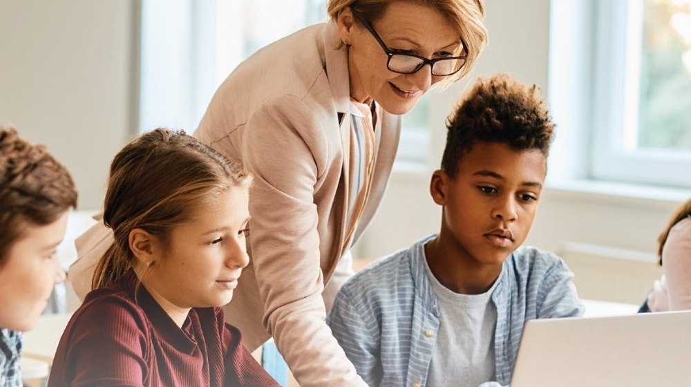 Picture of a teacher is giving instructions to three students.