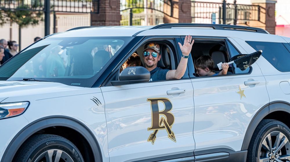 Man waving inside a car.