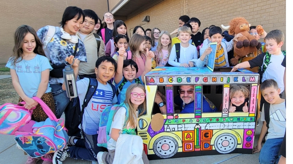 Elementary students taking a picture with one of the bus drivers.
