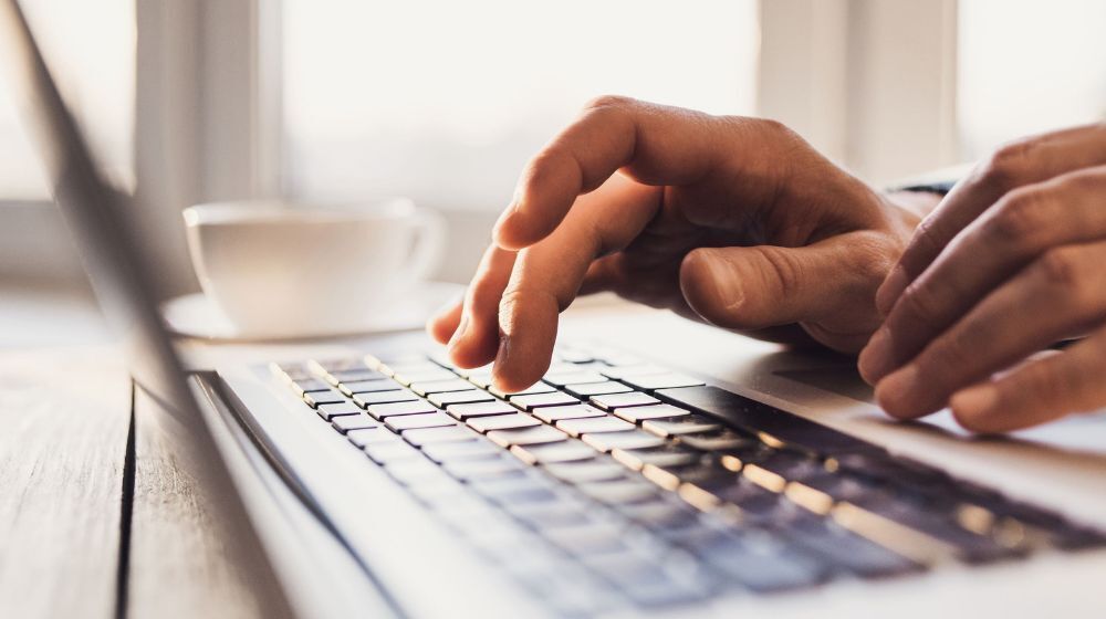 Person typing on a computer keyboard.