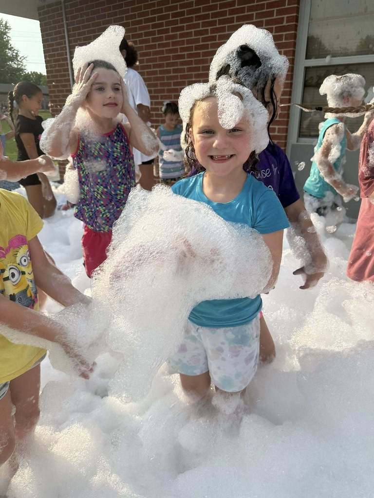 Kids playing in bubbles at school event.