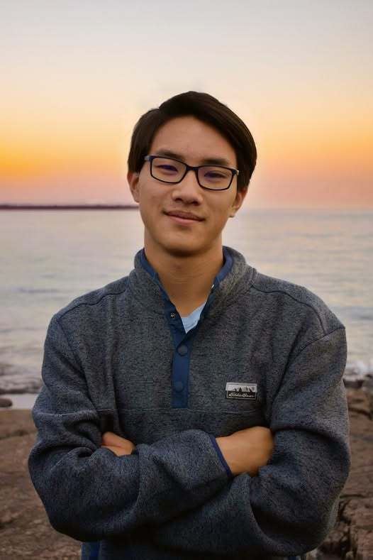 Image of Ernest Ting standing in front of water as the sun sets.