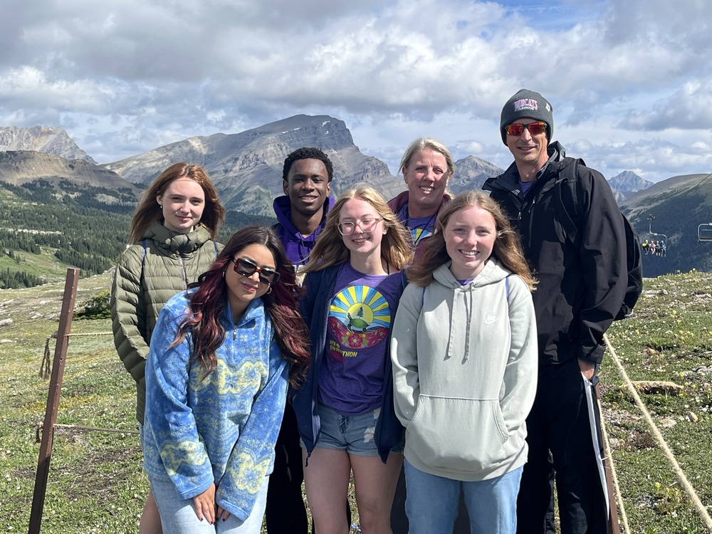 Image of students and staff with mountain in the background. 