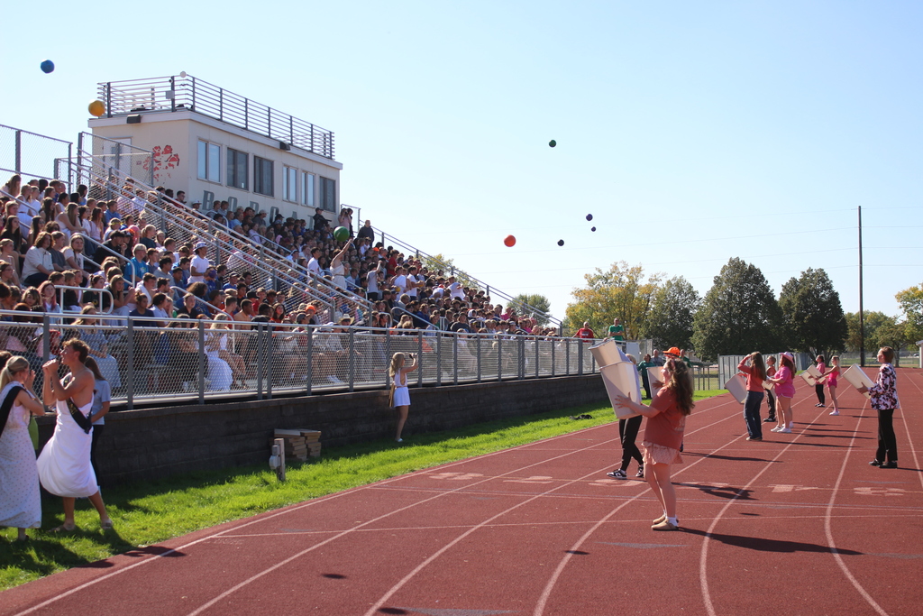 people catching balls in cans as they are thrown from the audiance for a game.