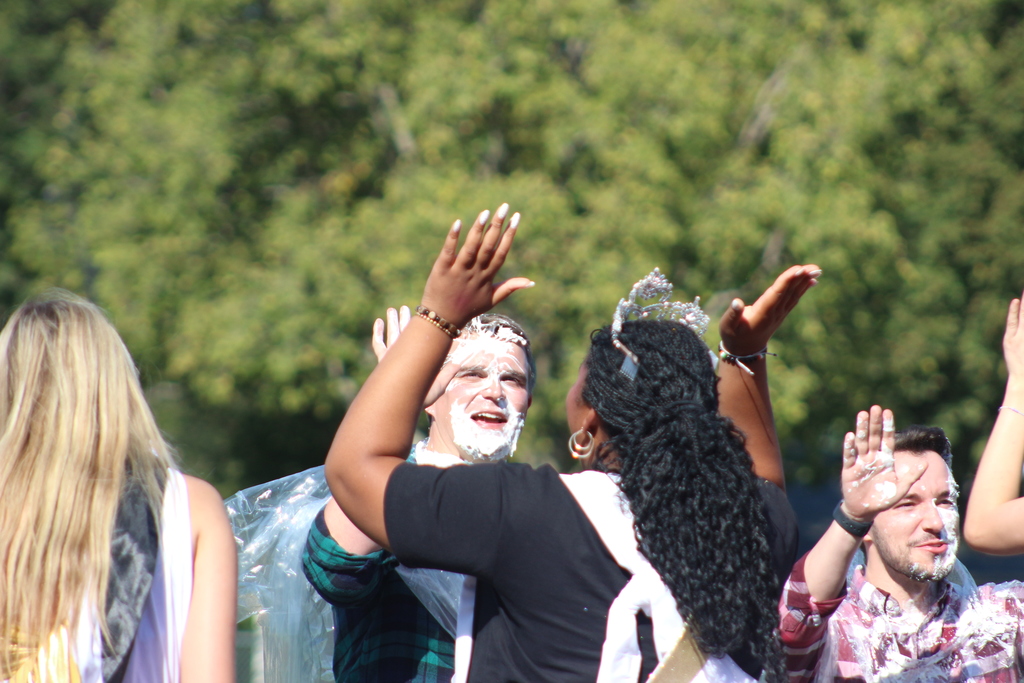 student high fiving a staff with pie on their face.