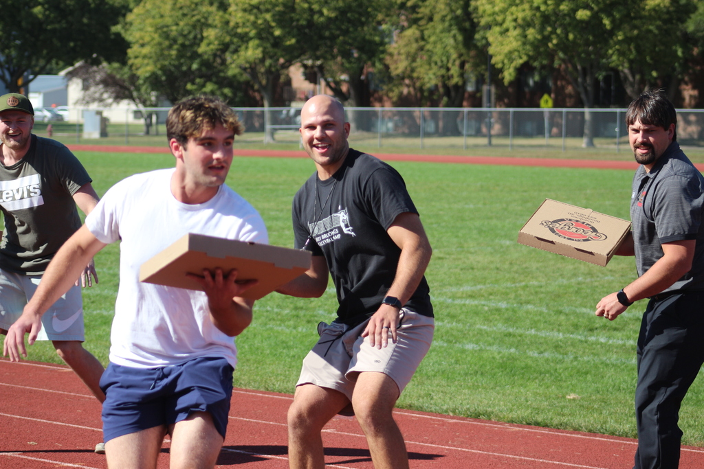 staff holding empty pizza boxes for a game.
