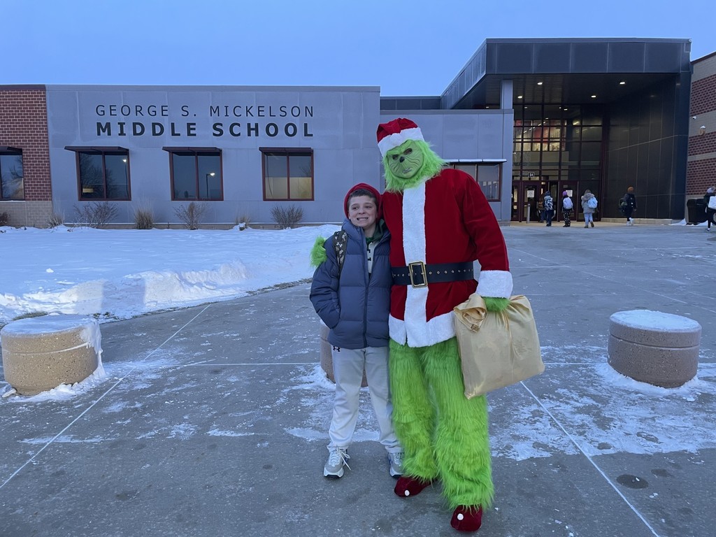 Student posing with a staff member dressed up as The Grinch. 