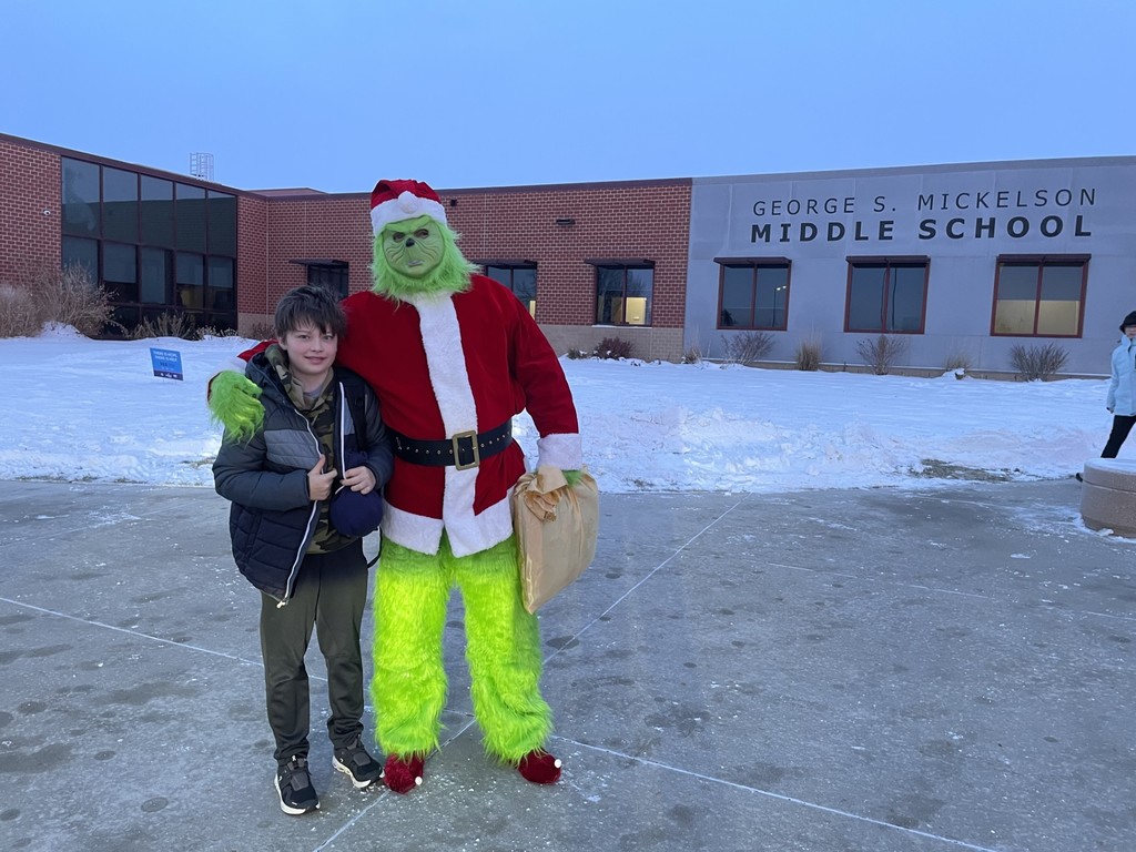 Student posing with a staff member dressed up as The Grinch. 