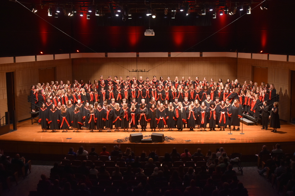 Choir singing. Dressed in black robes. 