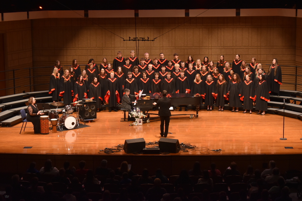 Choir singing. Dressed in black robes. 