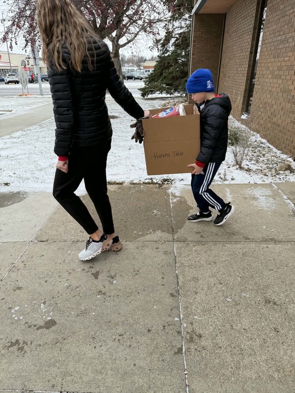 Two students carrying a box of items.