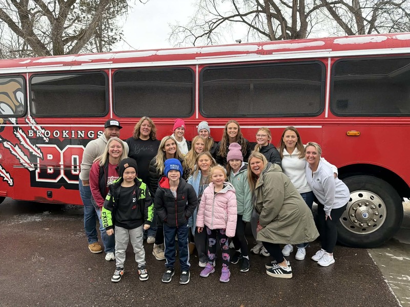 Group of staff and students standing in front of the bus.
