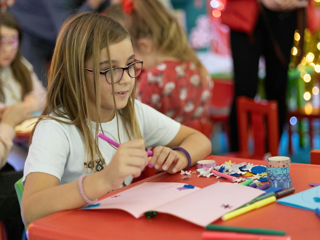 Student works on a craft project at a holiday party. 
