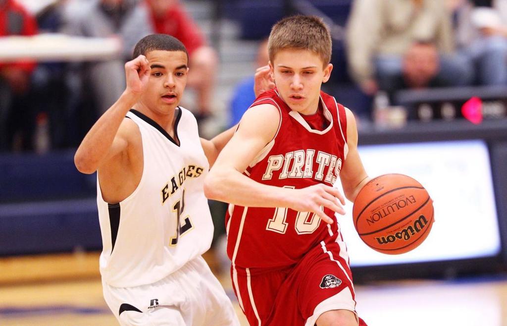 Two boys playing basketball in the school gym.