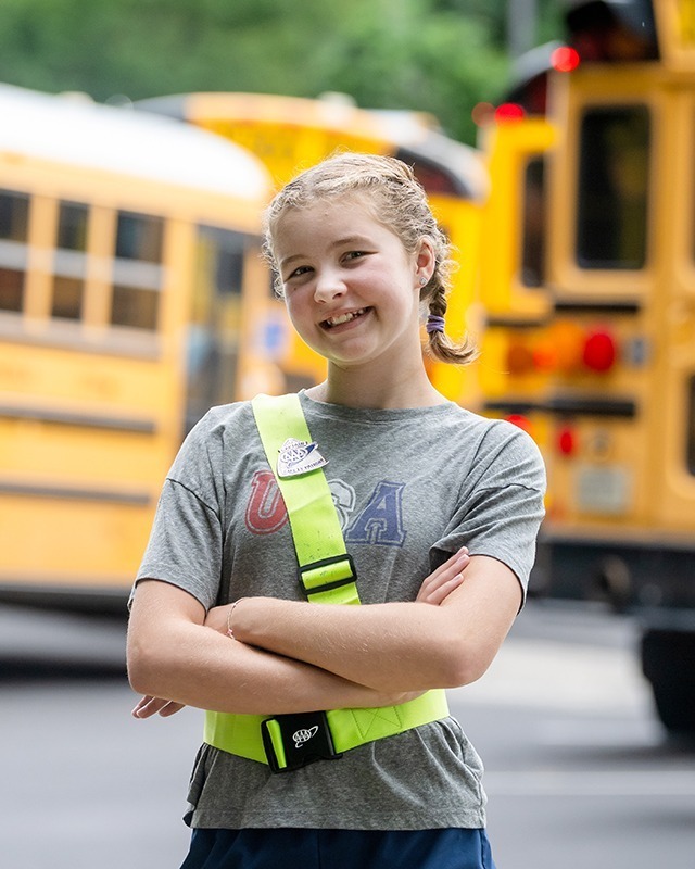student posing for picture in front of school buses