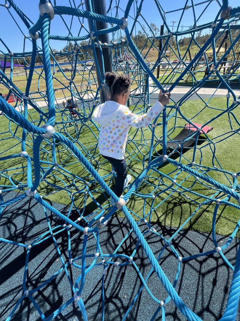 young kindergartener climbing s rope structure
