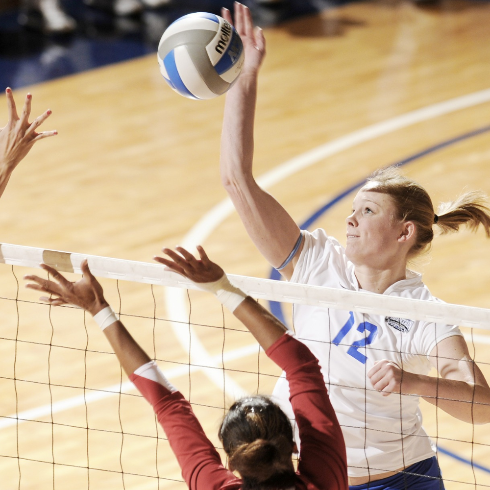 lady eagle volleyball player spiking a ball over the net