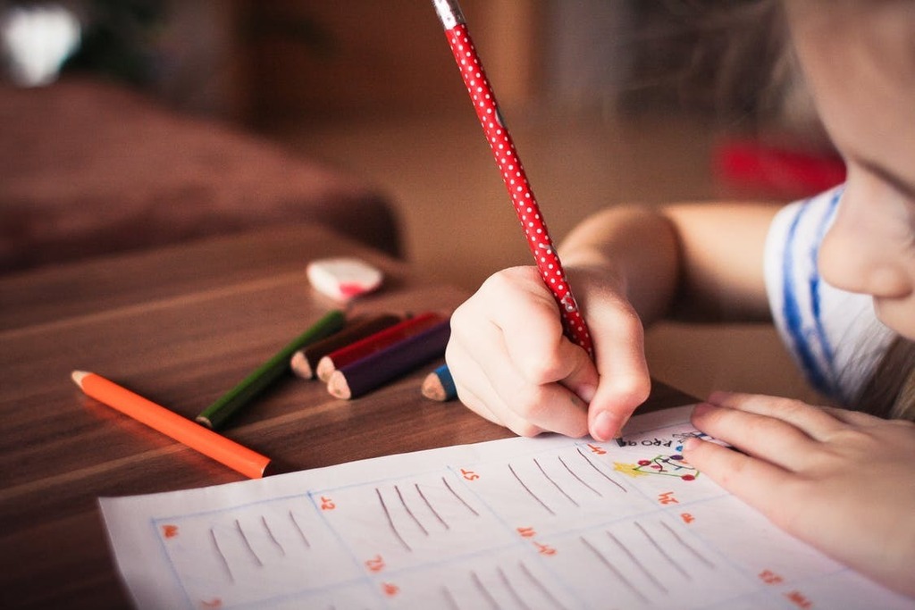 a student writing with a red pencil