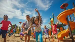 Students play on a yellow and green playground on a sunny day.