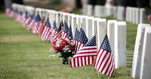 American Flags waiving in front of memorial headstones.