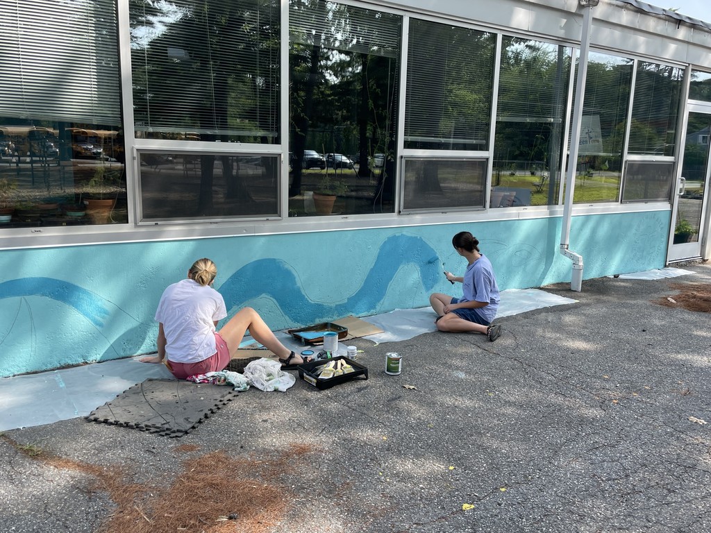 Students paining seascape on building