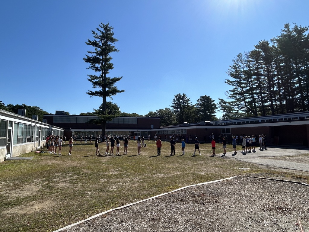 Students standing in a large circle outside.