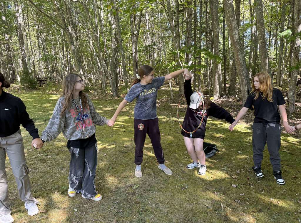 Students in a circle moving a hula hoop around the circle.