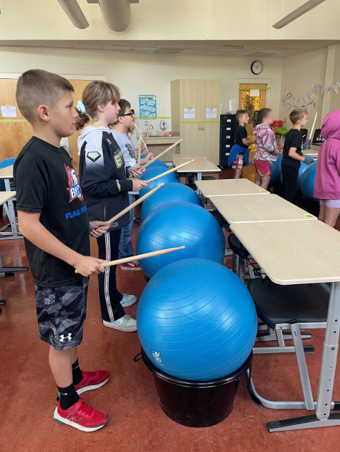 students standing playing drums alive