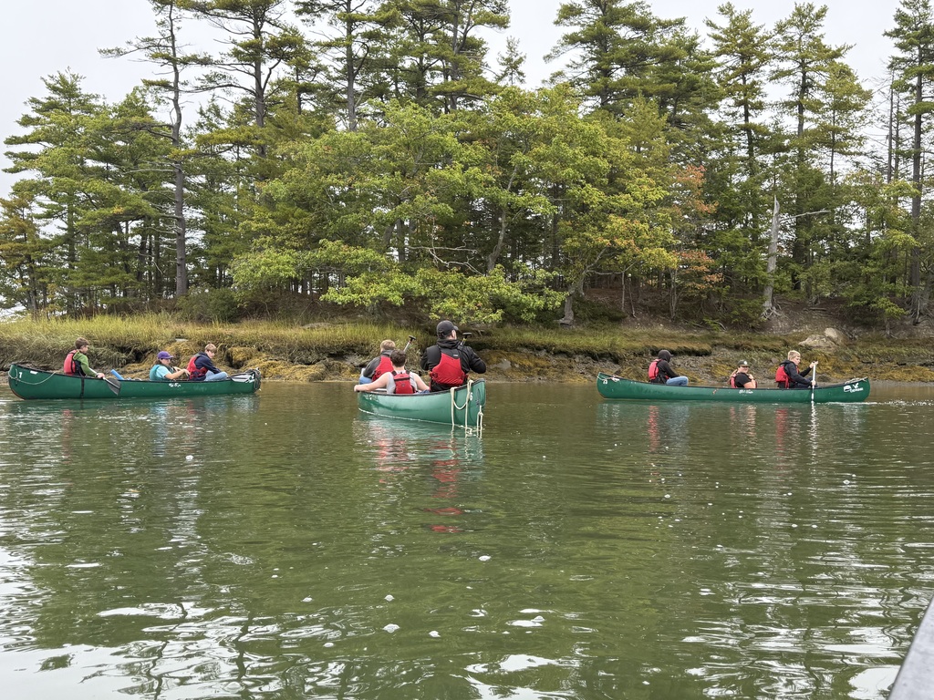 Student in a canoe paddling.
