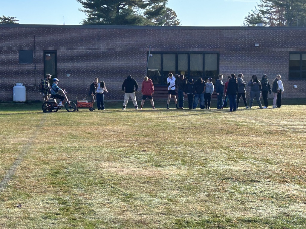 Students outside in a line moving wooden blocks.