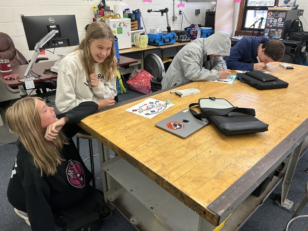 Four student sitting at a table using robots & markers.