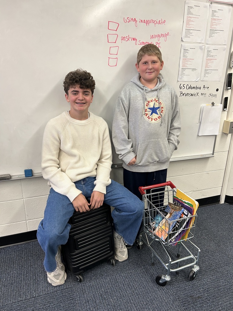 Students posing in a school hallway with unique bags as backpacks.